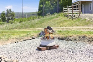 A gravel area with a fire pit, surrounded by a wooden fence and a building in the background.