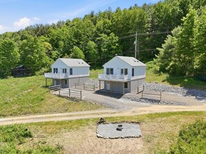 Two detached houses with separate porches, surrounded by a gravel driveway and a forested hillside. - Lakeview Retreat Near Finger Lakes! (Lawrenceville)