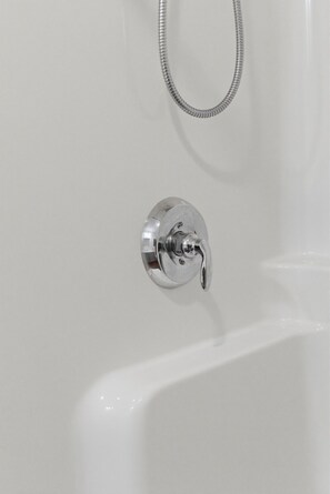 A bathtub with a chrome faucet and a shower hose.