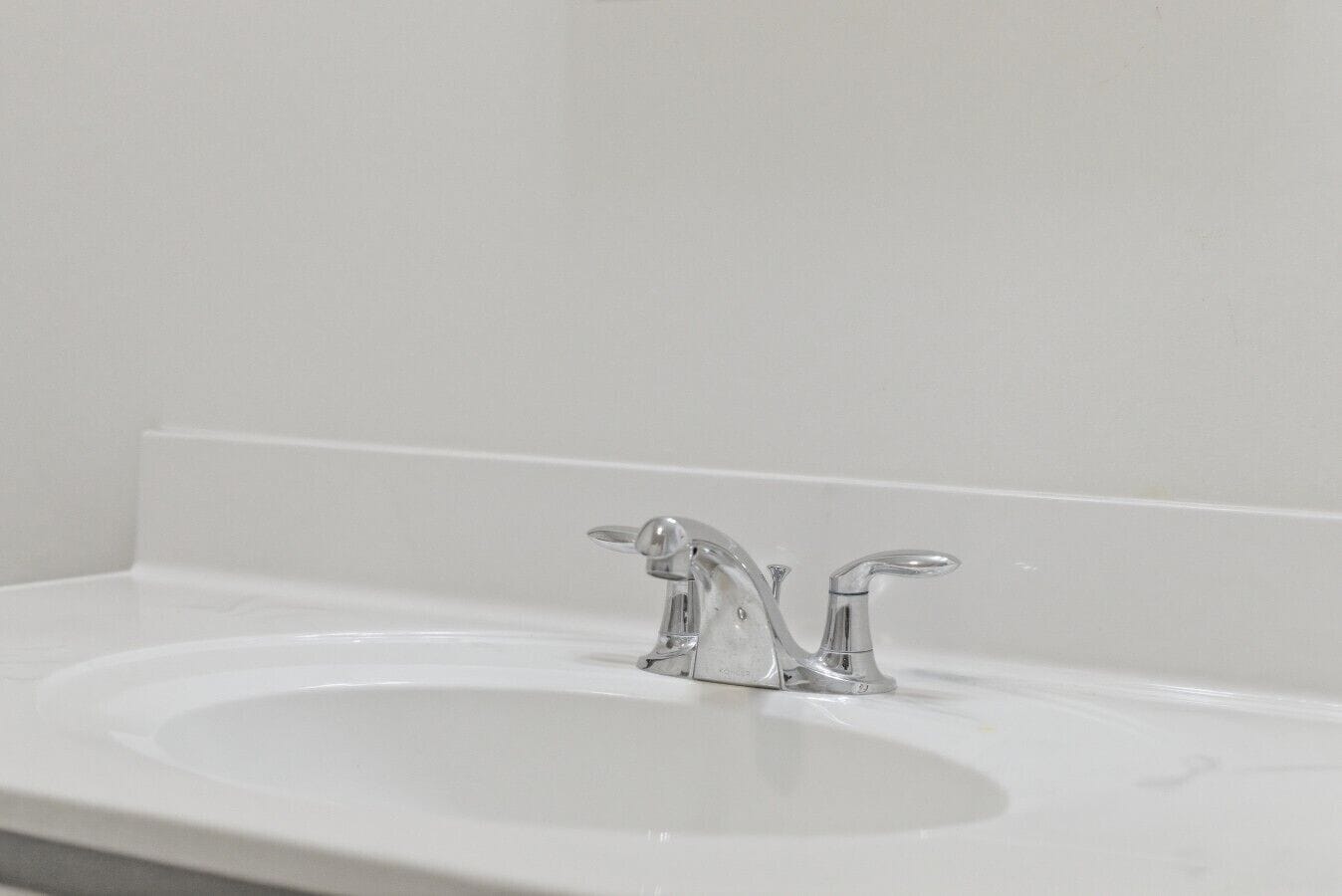 A bathroom sink with a chrome faucet and a white countertop.