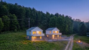 Two detached houses with balconies, a gravel path, and a forested background. - Lakeview Retreat Near Finger Lakes! (Lawrenceville)
