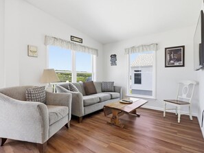 A living room with a sofa, armchair, wooden coffee table, and a white chair.