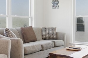 A living room with a sofa, patterned pillows, a coffee table, and a wall sign. - Lakeview Retreat Near Finger Lakes! (Lawrenceville)