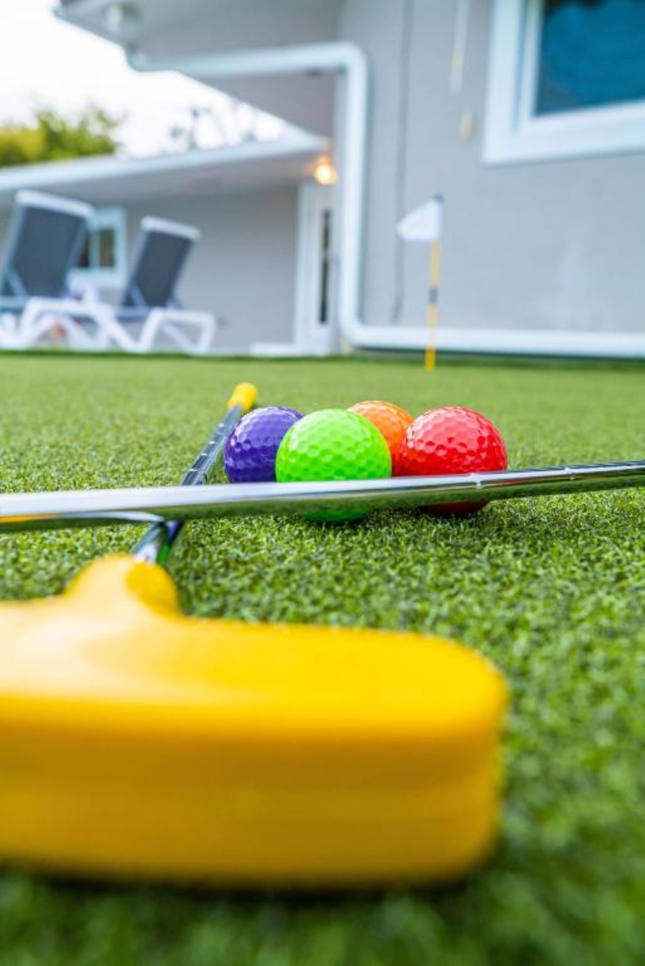 Primer plano de un putting green de golf, con un putter y pelotas de golf al frente.