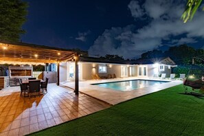 A modern house with a swimming pool, outdoor seating, and a covered patio area. - Cozy Villa Grill Mini Golf Pool (North Miami Beach)