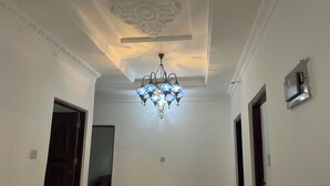 A hallway with a decorative ceiling, a chandelier, and a wall-mounted air conditioning unit. - Spacious 4 bedroom Home with Modern Comfort Nungwi (ZANZIBAR)