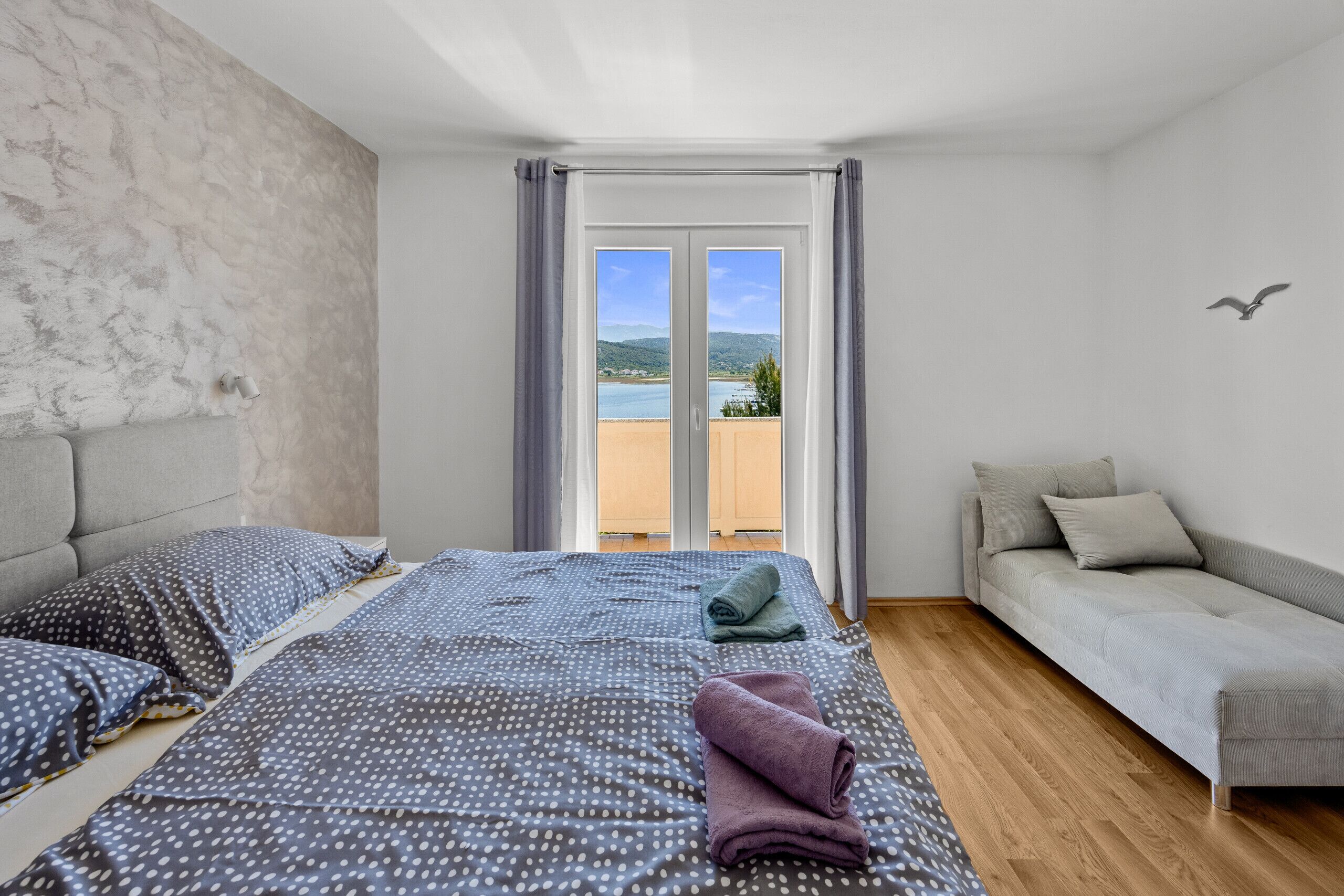 Quarto com cama, sofá e vista para o exterior.