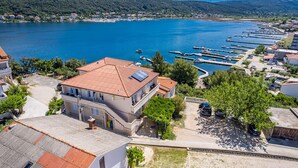 Un pueblo costero con un puerto deportivo, edificios con tejados rojos y una vista despejada del mar.
