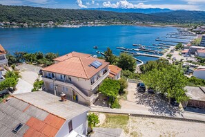 A coastal town with a marina, buildings with red-tiled roofs, and a clear view of the sea.