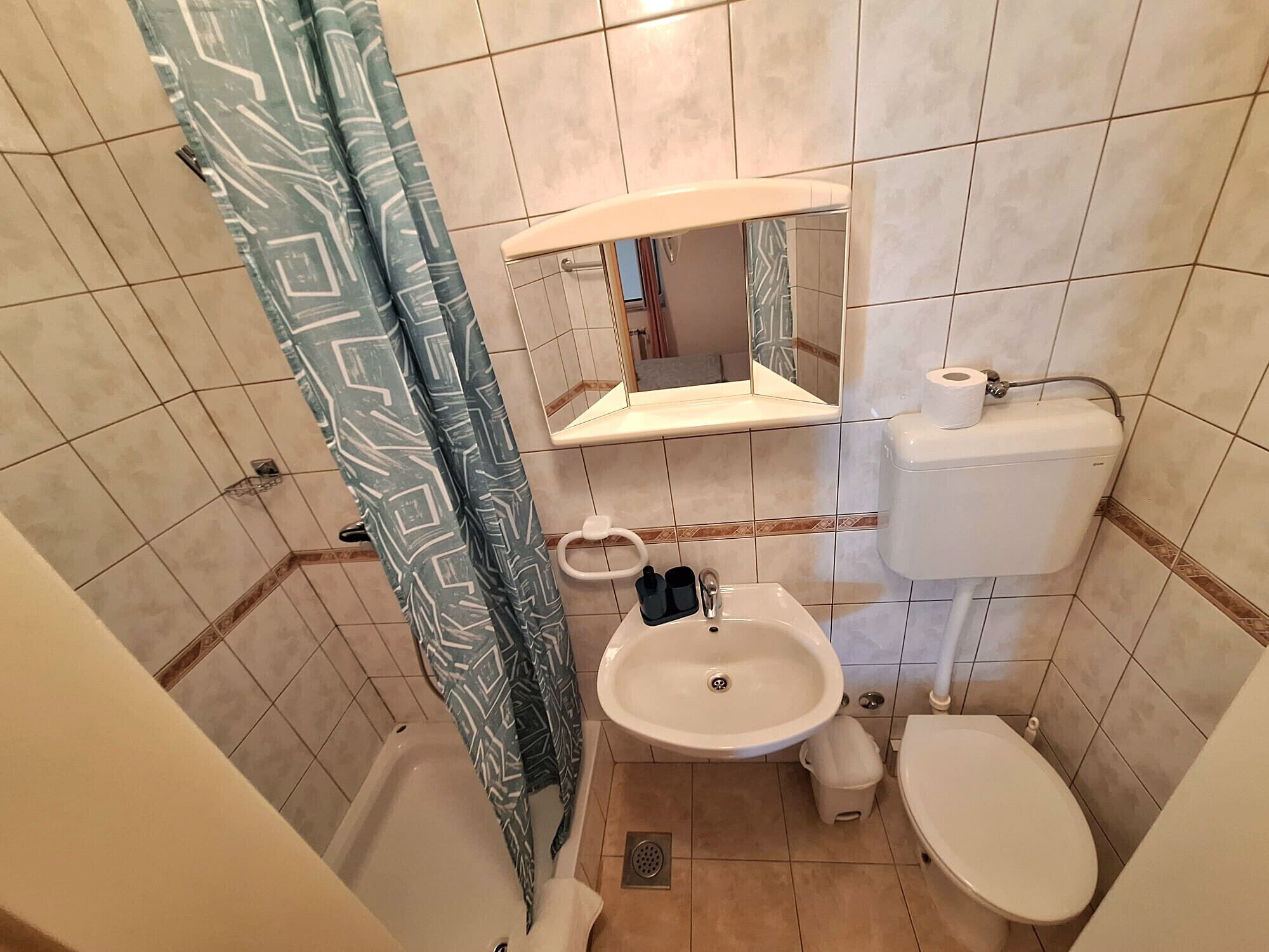 Une salle de bain équipée d’une baignoire, de toilettes, d’un lavabo et d’un miroir au-dessus du lavabo.