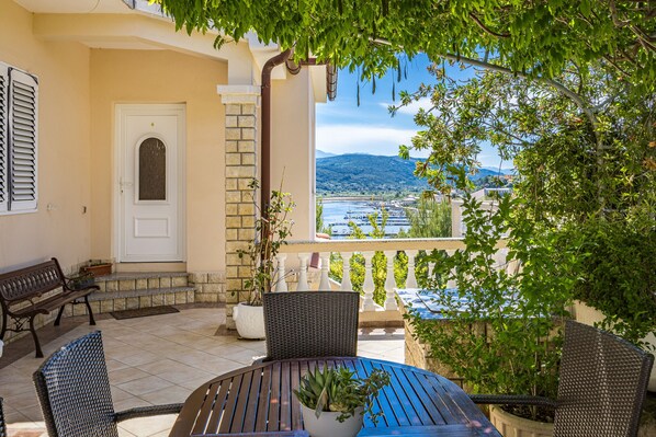 A balcony with a view of the sea, a door, and outdoor furniture.