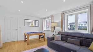 A room with a pool table, a sofa, a lamp, and a window with curtains. - 3-Bed House with Parking | Ideal for Contractors (Aylesbury)