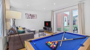 A living room with a pool table, a sofa, a TV, and a large window. - 3-Bed House with Parking | Ideal for Contractors (Aylesbury)