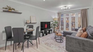 A modern living room with a dining area, a TV, and a sofa.
