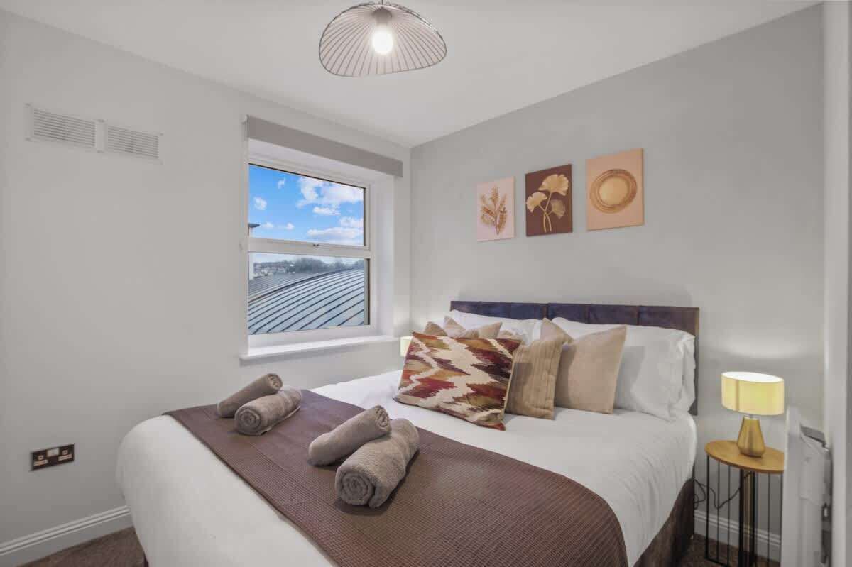 Hotelkamer met een groot bed, een raam met uitzicht op spoorlijnen en een plafondlamp.