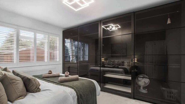 Ein Schlafzimmer mit einem Bett, einem großen Kleiderschrank und einer Deckenleuchte.