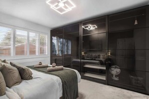 A bedroom with a bed, a large wardrobe, and a ceiling light fixture. - Cosy 2-Bed Maisonette | Driveway Parking & Garden (Potters Bar)