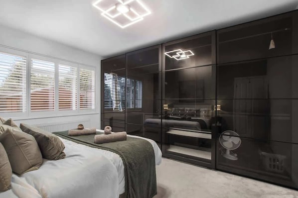 Een slaapkamer met een bed, een grote kledingkast en een plafondlamp.