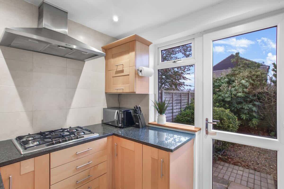 A kitchen with a gas stove, microwave, and wooden cabinets.