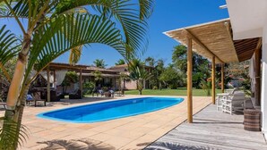 A swimming pool with a wooden deck, outdoor furniture, and a covered area with a pergola. - POUSADA RECANTO TRANCOSO (Porto Seguro)