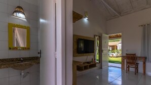A bathroom with a sink, mirror, and television. - POUSADA RECANTO TRANCOSO (Porto Seguro)