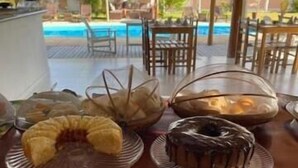 A dining table with various desserts and utensils, overlooking a pool area. - POUSADA RECANTO TRANCOSO (Porto Seguro)