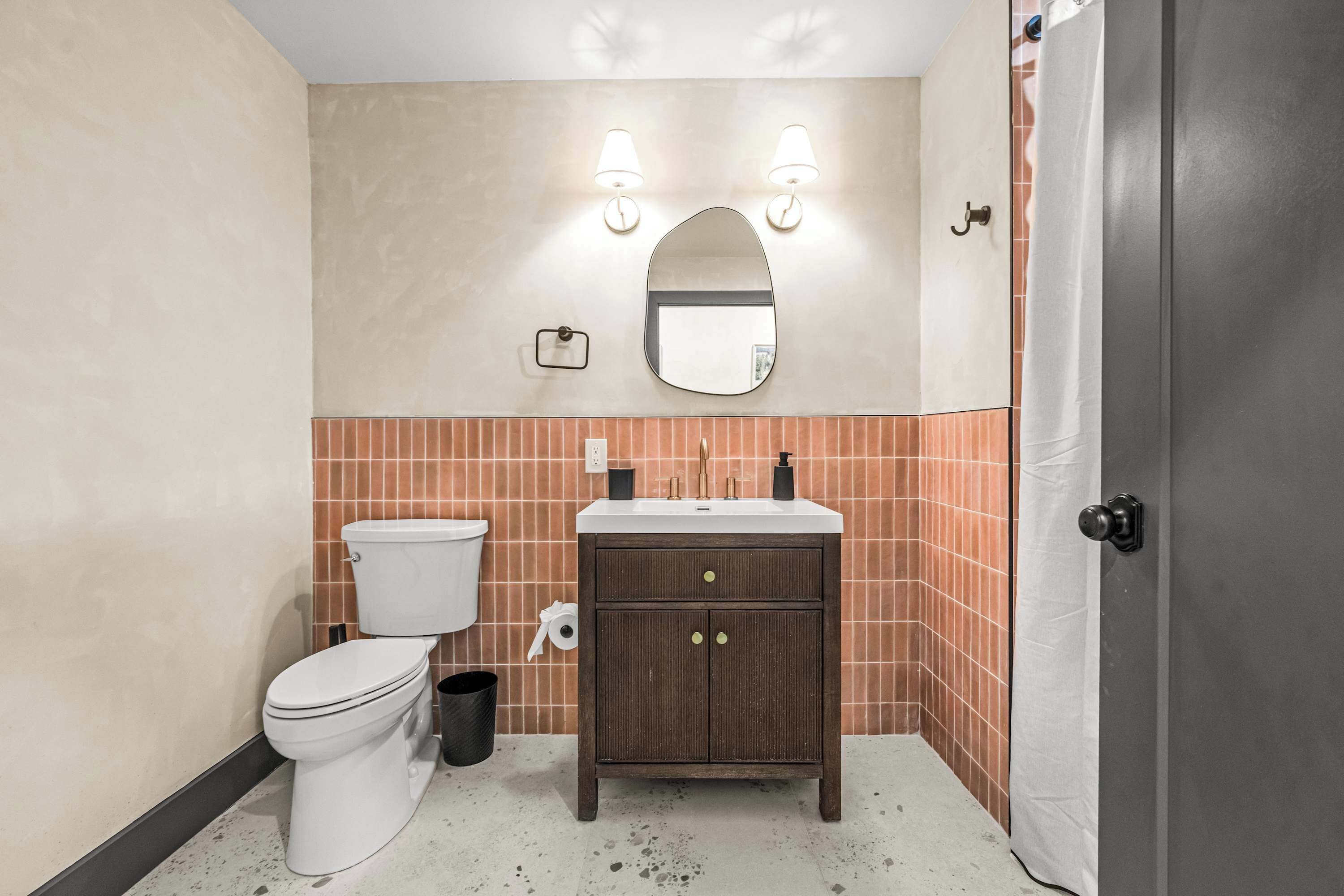 Une salle de bain équipée de toilettes, d’un lavabo, d’un miroir et d’un distributeur de serviettes.