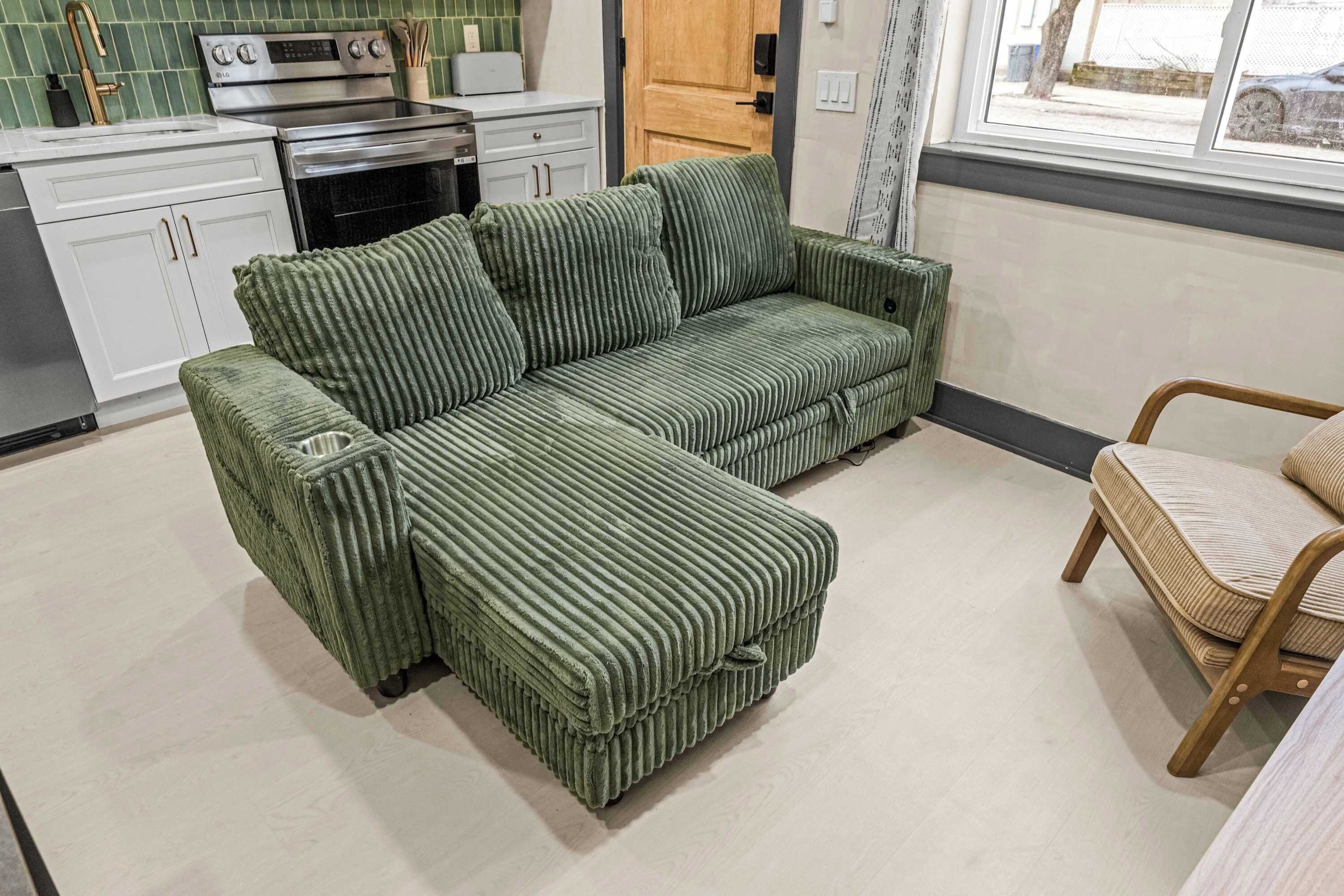 A green-striped sofa in a modern kitchen with white cabinets and a wooden door.
