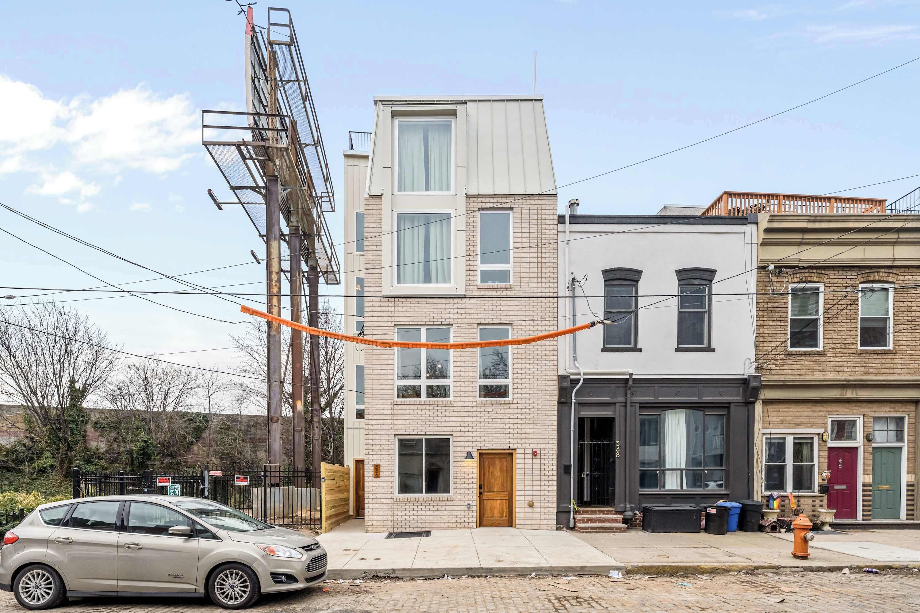 A multi-story building with a brick facade, a fire hydrant on the sidewalk, and a car parked in front.