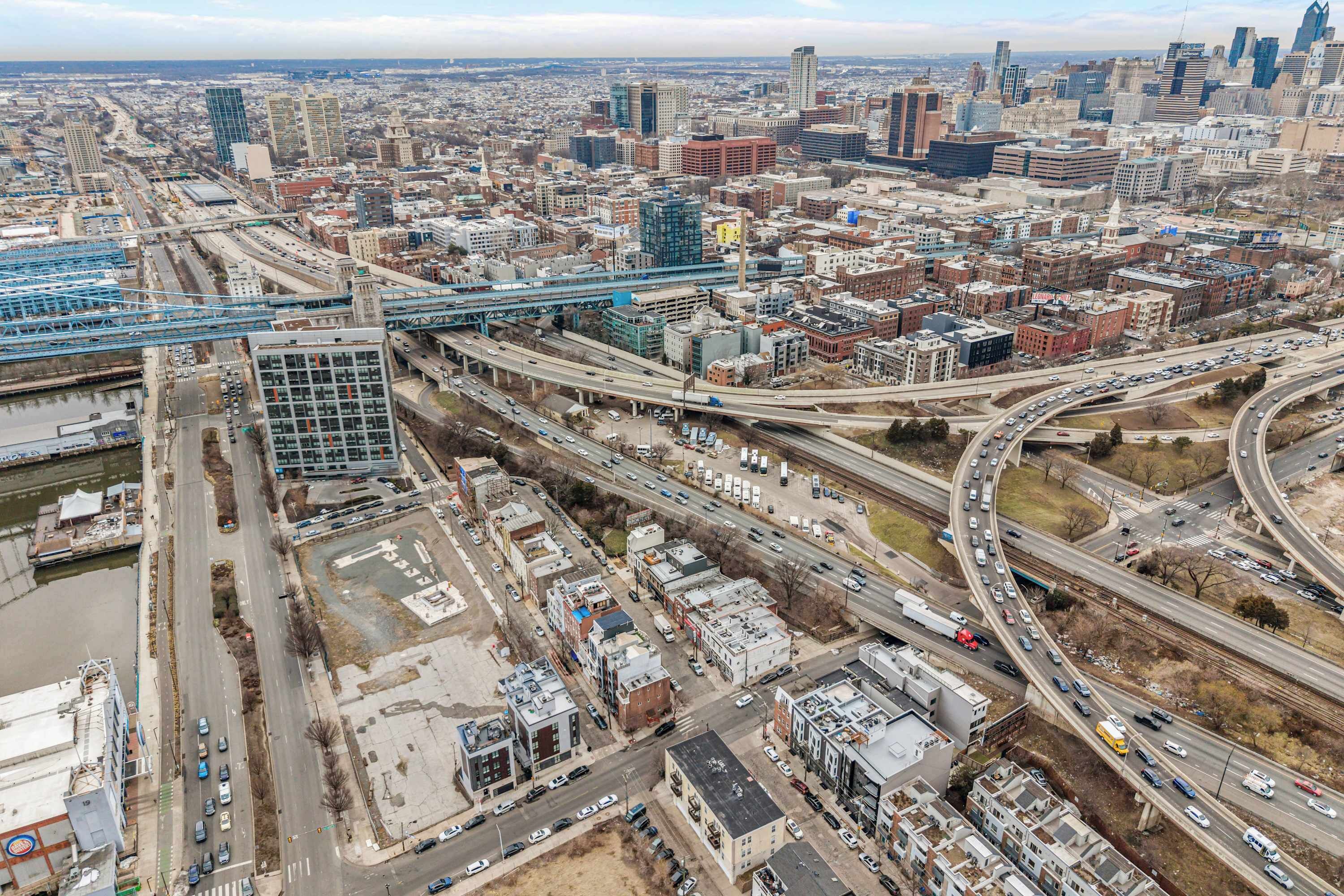 An aerial view of a cityscape with multiple highways, buildings, and a bridge.