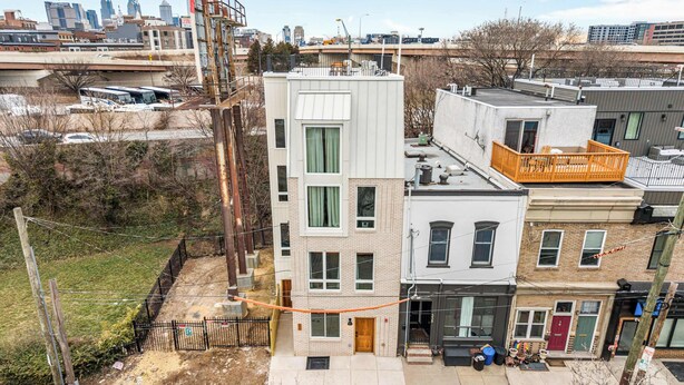 Un edificio residencial de varios pisos con un hidrante visible, un patio cercado y una vista despejada del horizonte urbano circundante.