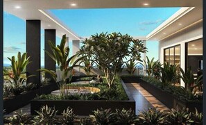 A modern indoor garden with various plants and a central water feature. - Southport 2BR Retreat | Rooftop Infinity Pool (Southport)