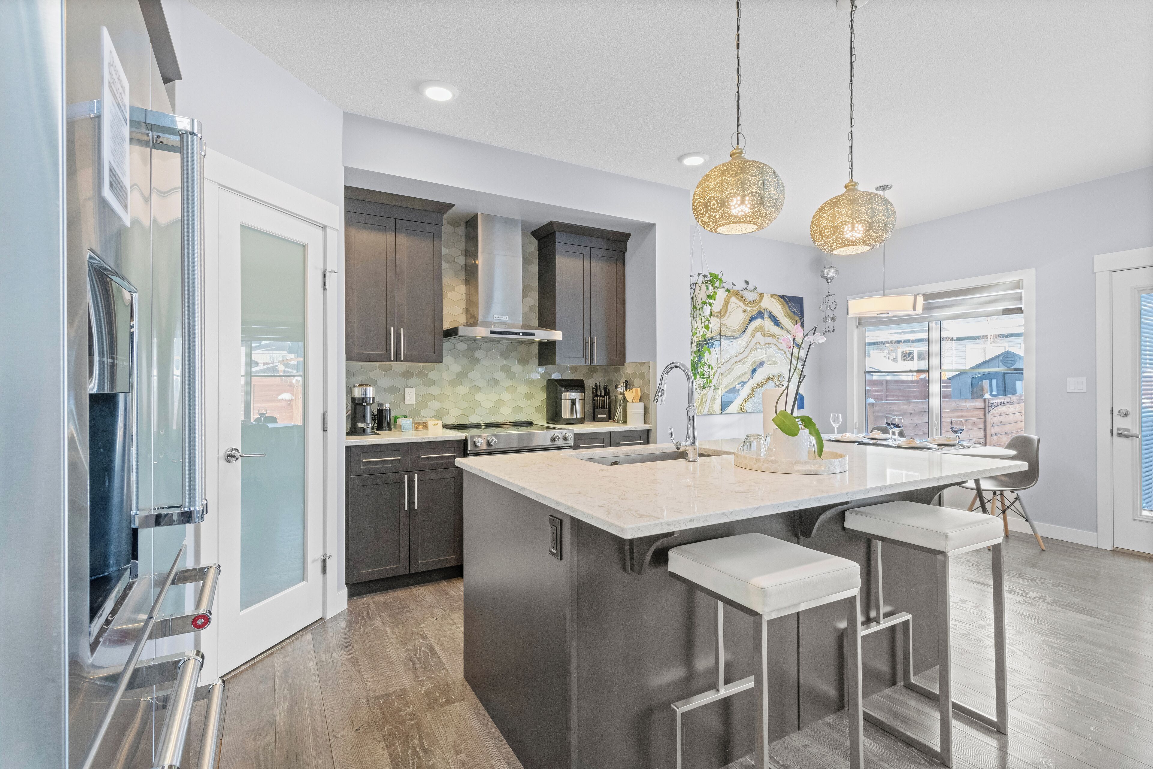 A modern kitchen with a large island, stainless steel appliances, and pendant lighting.