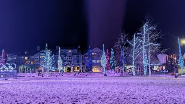 Een hotel met meerdere gebouwen, waarvan sommige verlichte bomen en een met sneeuw bedekte grond hebben.
