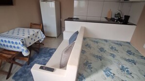 A compact living space with a sofa, a small table, a refrigerator, and a kitchenette area.