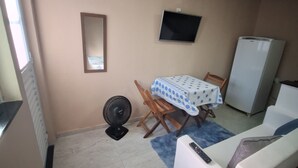 A compact living space with a dining table, a sofa, a TV, and a refrigerator.