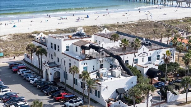A coastal hotel with a parking lot, beach view, and a pier in the background. - Beachside Oasis I Walk to the Beach I Ocean view I (Jacksonville Beach)