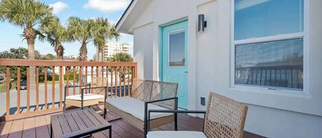 A balcony with wicker furniture and a view of palm trees.