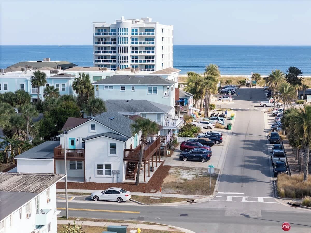 A coastal hotel with a parking lot, a stop sign, and a view of the ocean.
