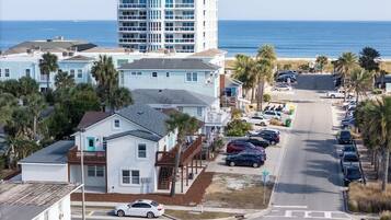 A coastal hotel with a parking lot, a stop sign, and a view of the ocean.