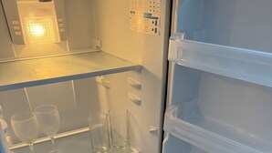 An open refrigerator with clear glassware on the top shelf and water bottles on the bottom shelf. - Tranquil 2-bedroom apartment with AC in welcoming Tulum (Tulum)