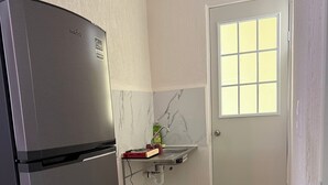 A compact kitchen with a built-in refrigerator, a small countertop, a window, and a door. - Tranquil 2-bedroom apartment with AC in welcoming Tulum (Tulum)