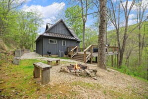 A cabin with a deck, a fire pit, and a picnic table. - Snuggle Inn – Cozy Pet Friendly Forest Cabin with Hot Tub Near Red River Gorge (Stanton)