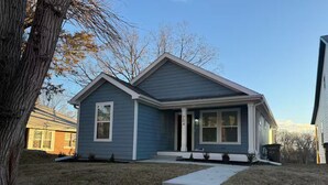 A single-story house with a gabled roof, a front porch, and a visible front door. - Charming brand new home! Walk to everything! (Atchison)