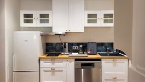 A compact kitchen with white cabinets, a Bosch refrigerator, a coffee maker, and a dishwasher. - Grand T2 Cosy -Rouen historic center near Hôtel de Ville - L'Hauss'Rouennais (Rouen)