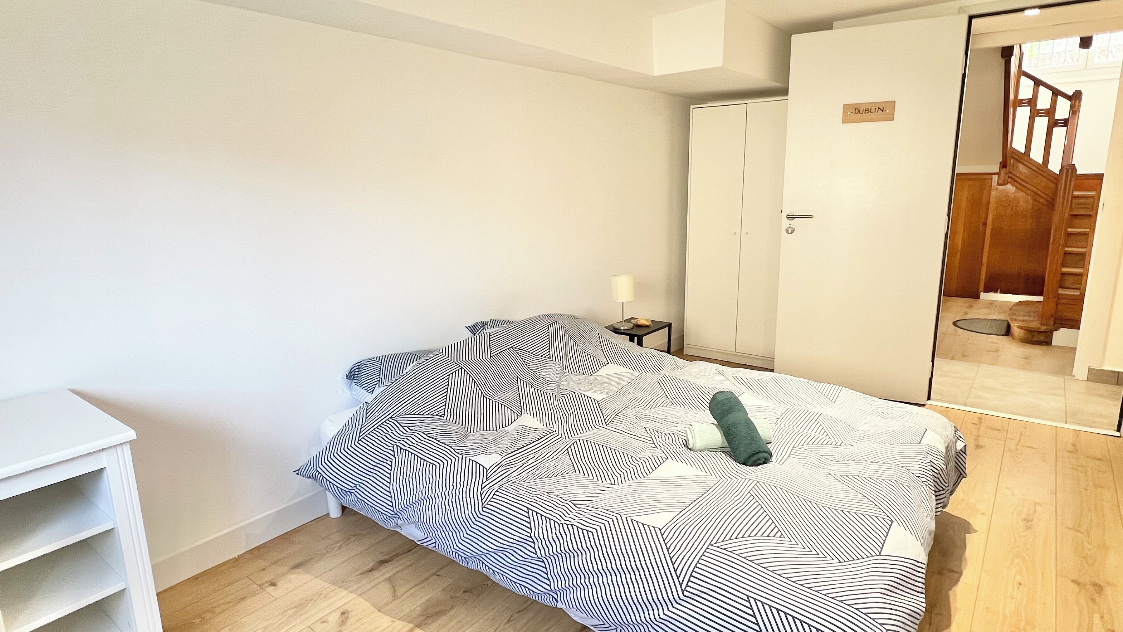A bedroom with a bed, a wardrobe, a nightstand, and a mirror.