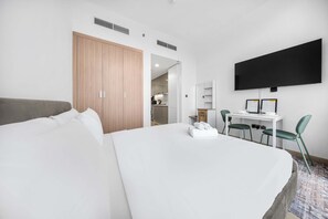 Ein Hotelzimmer mit einem großen Bett, einem Schreibtisch mit Stuhl, einem Fernseher und einem Kleiderschrank.