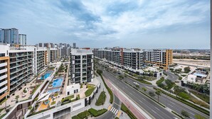 Una zona residenziale moderna in città, con edifici alti, una strada centrale e un complesso di piscine.