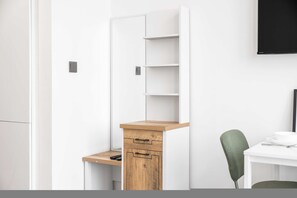 Ein kompakter, moderner Raum mit Schreibtisch, Stuhl und Wand-Fernseher.