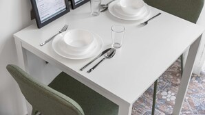 Una tavola da pranzo ordinata con piatti bianchi, posate e un bicchiere, insieme a un espositore per il menu.